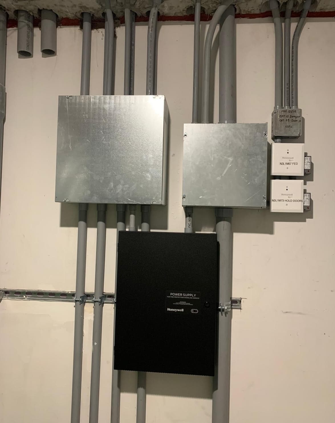 Conduit, fire alarm modules, and ABB drive on a mechanical room wall